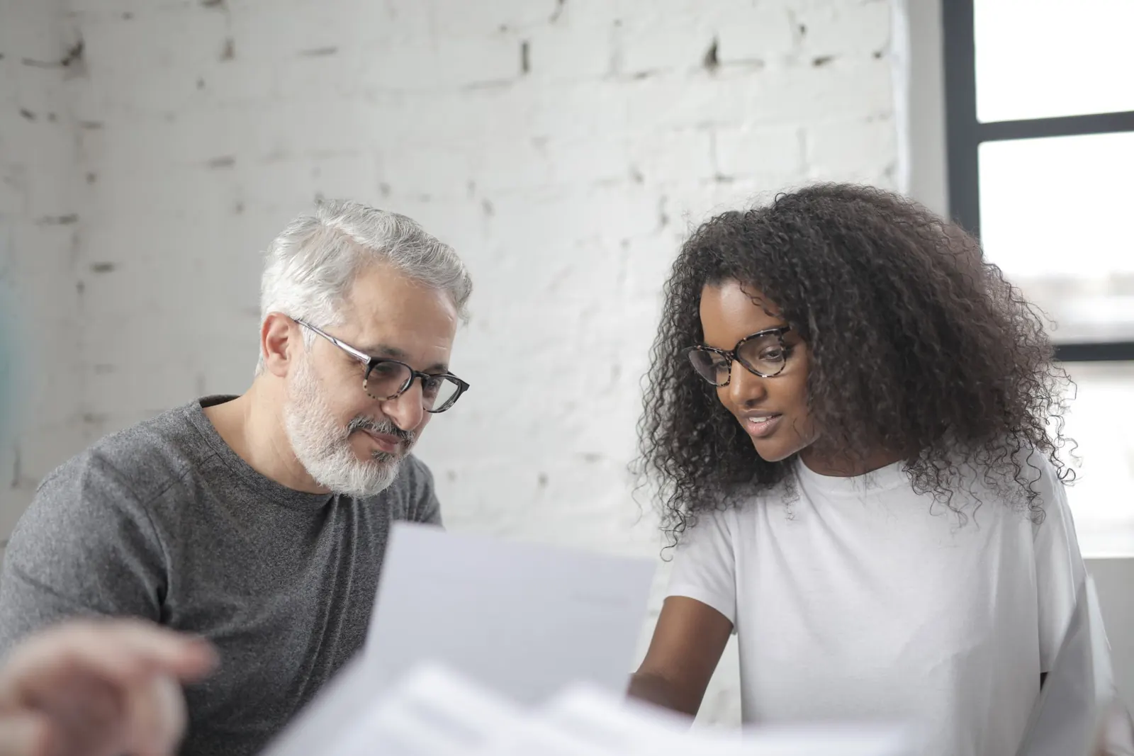 An older and a younger colleague reviewing documents together in an office