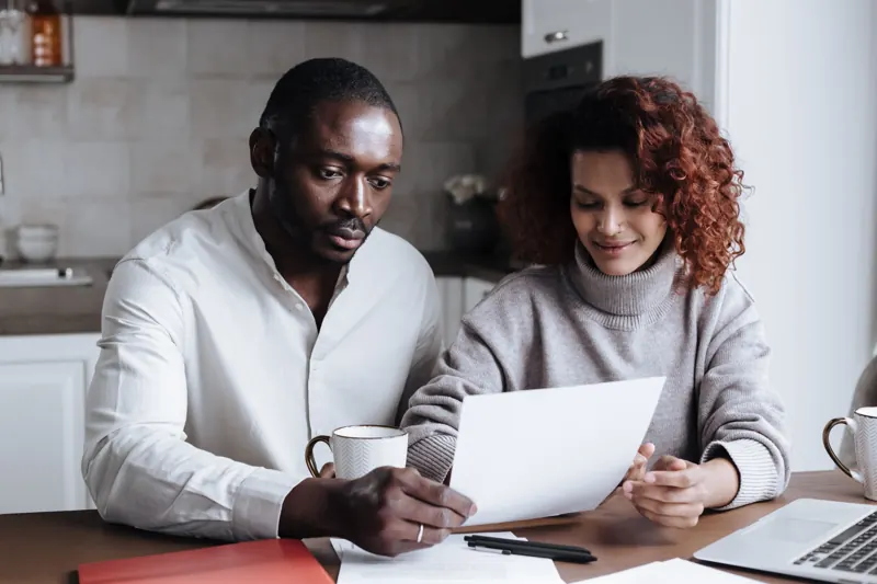 Two people reviewing paperwork together at a kitchen table