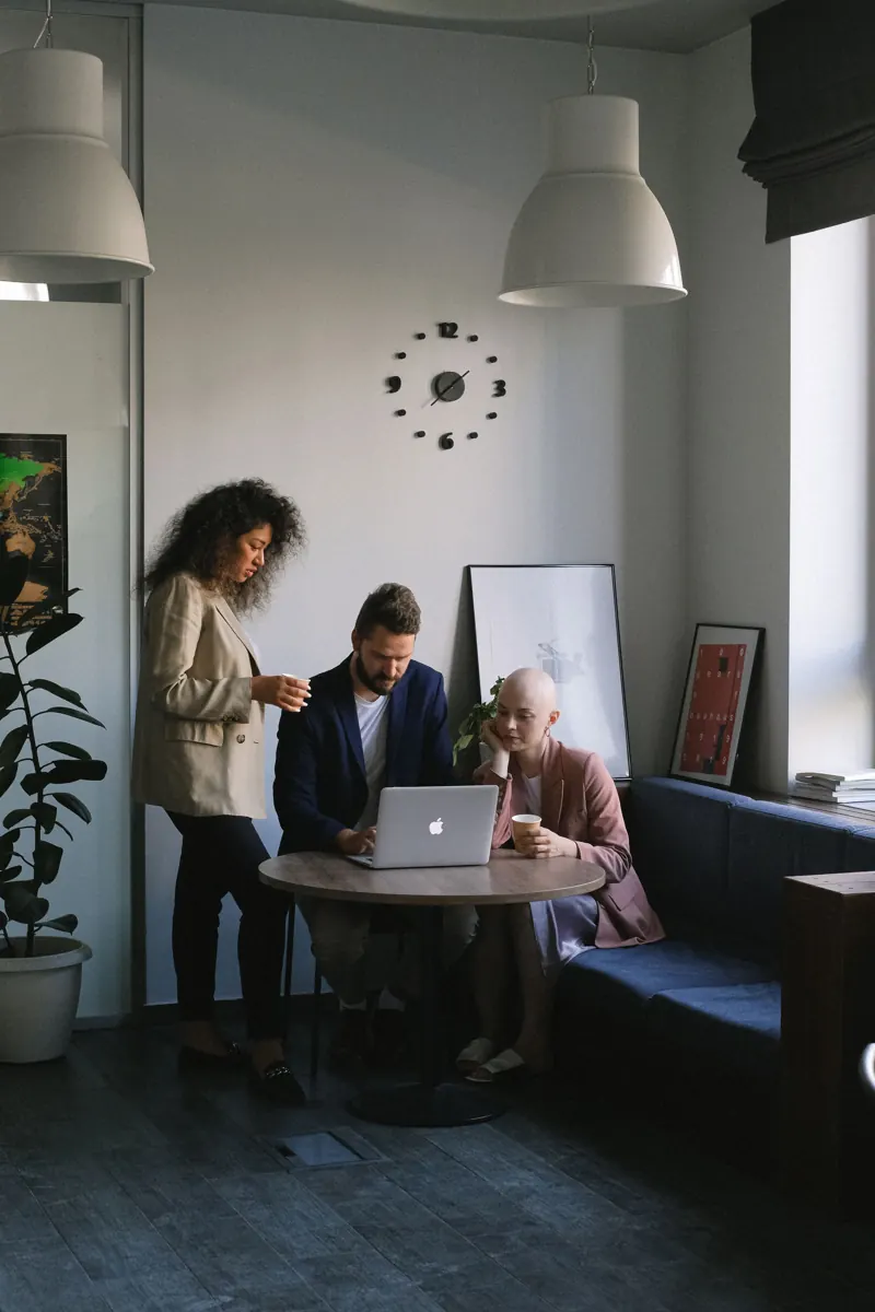 Coworkers talking over a laptop in a bright office